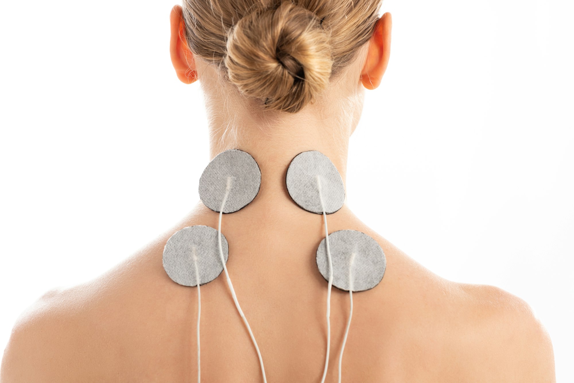 Back view of young woman with electro stimulation electrodes on neck isolated on white